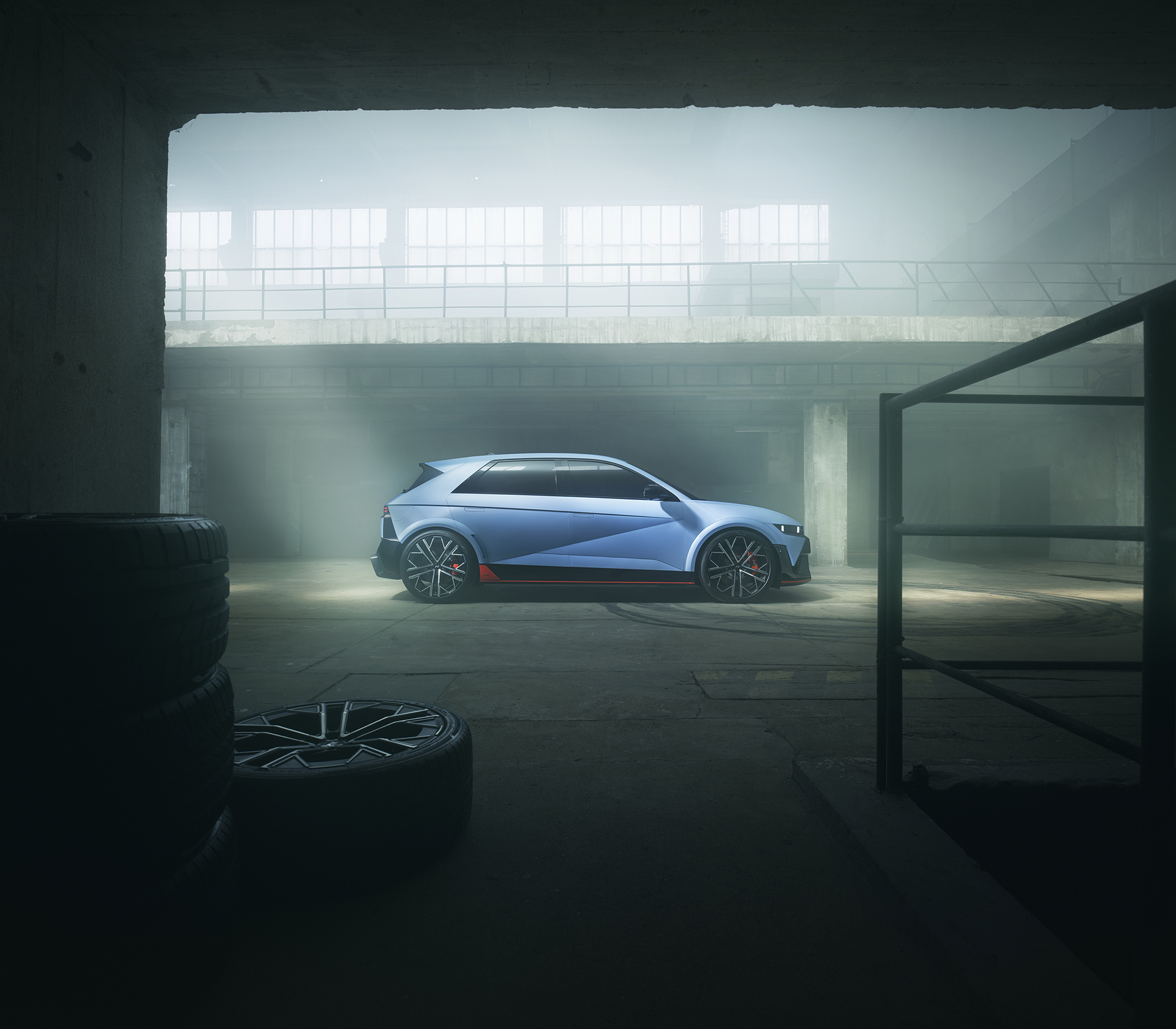 Hyundai IONIQ 9 von der Seite  in blau in einem geschlossenem Raum, durch das von oben kommende Licht wirkt das Bild vernebelt