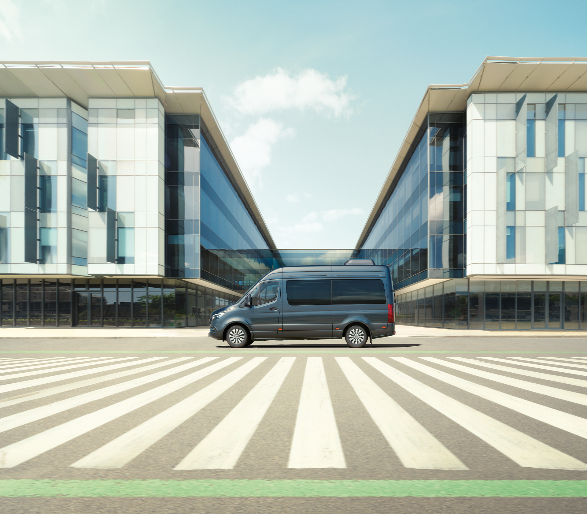 Mercedes-Benz Sprinter in grau von der Seite vor einem Gebäude mit einem Zebrastreifen im Vordergrund