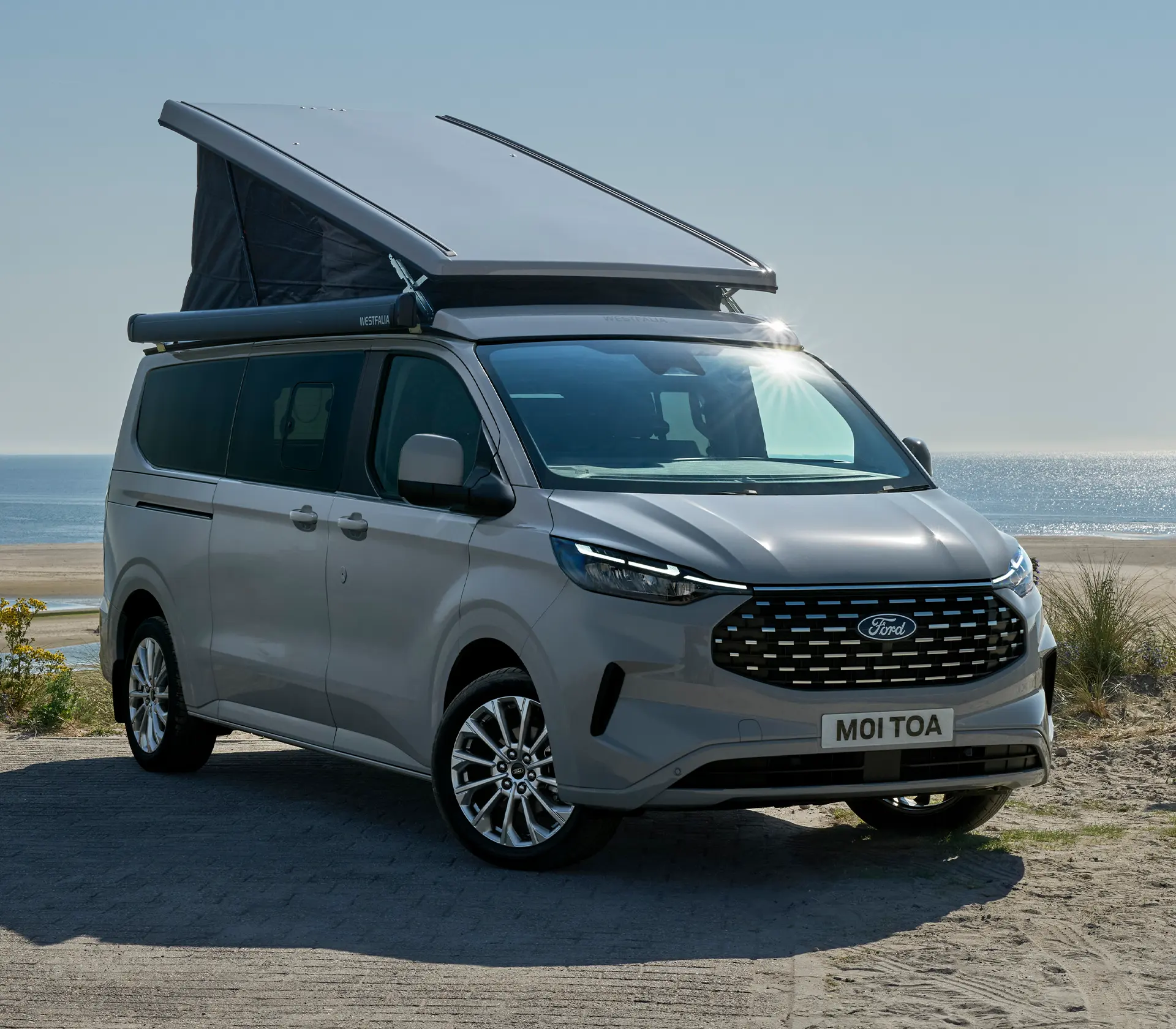 grauer Ford Nugget mit Meer im Hintergrund und gehobenem Dach