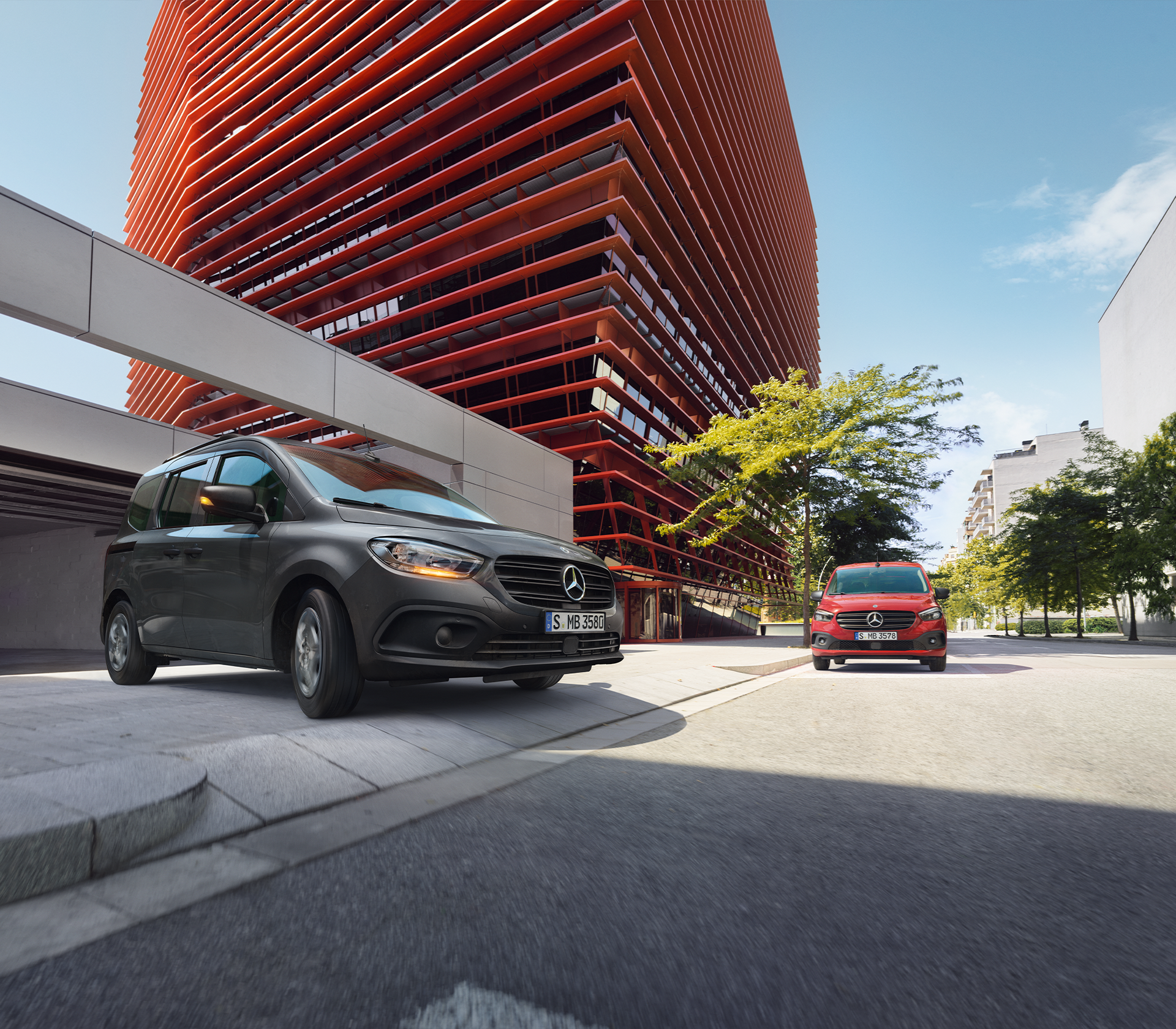 Zwei Mercedes-Benz Citan Fahrzeuge – schwarz und rot – vor moderner Architektur, bereit für urbane Mobilität.