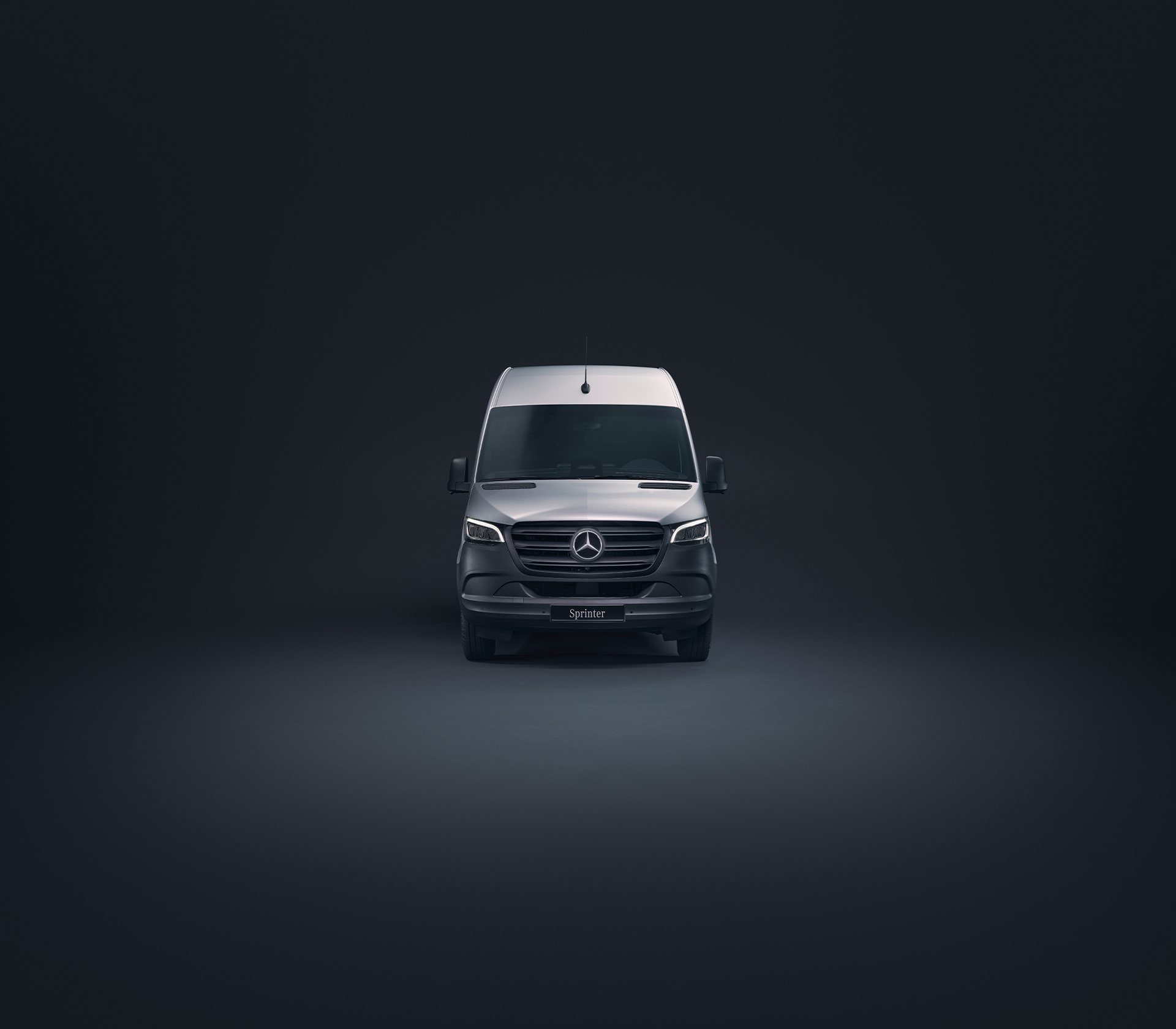 Mercedes-Benz Sprinter in grau Frontansicht in einer schwarten Studioumgebung