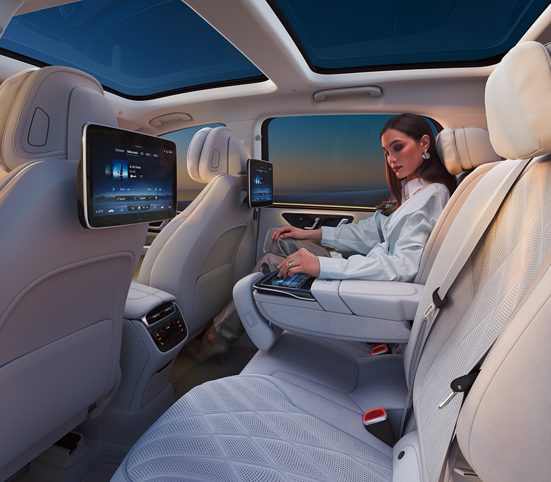 Mercedes-Benz EQS SUV Innenansciht auf weiße Ledersitze hinten und die Bildschirme und eine Frau, die hinten sitzt