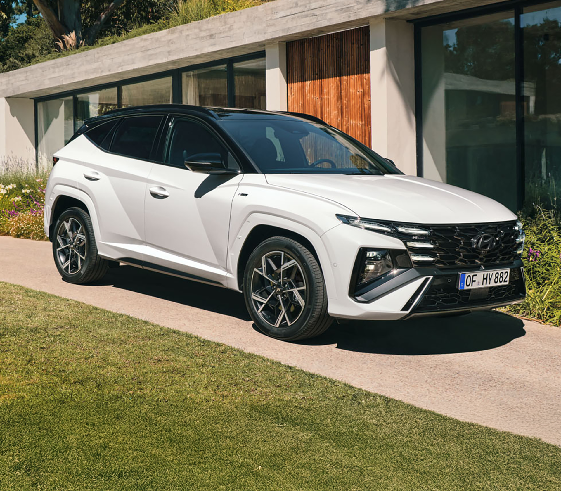 Hyundai TUCSON schräg von der Seite Auto in weiß mit einem modernen Gebäude im Hintergrund