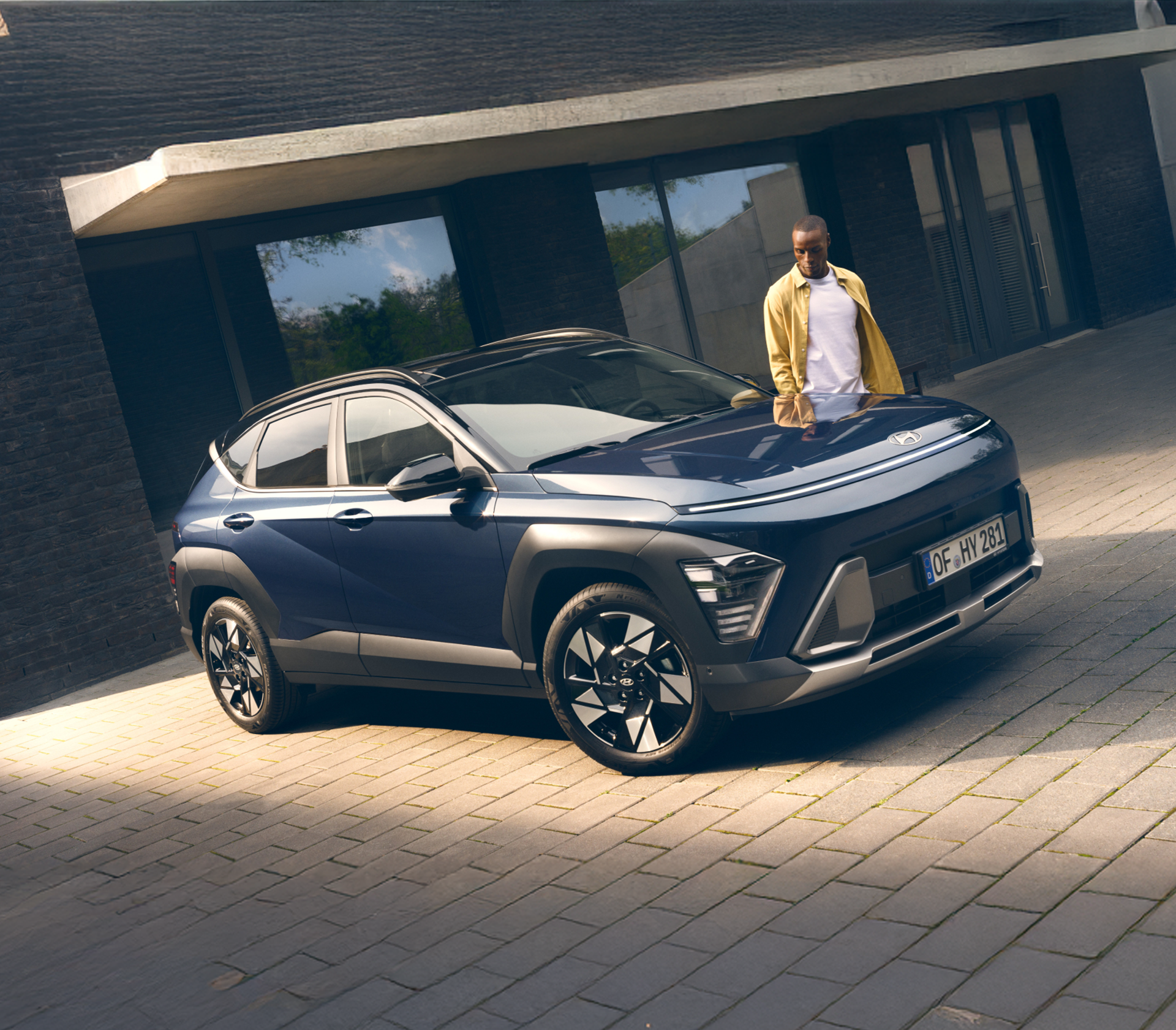 Hyundai KONA  in dunkelblau mit einer Frau daneben