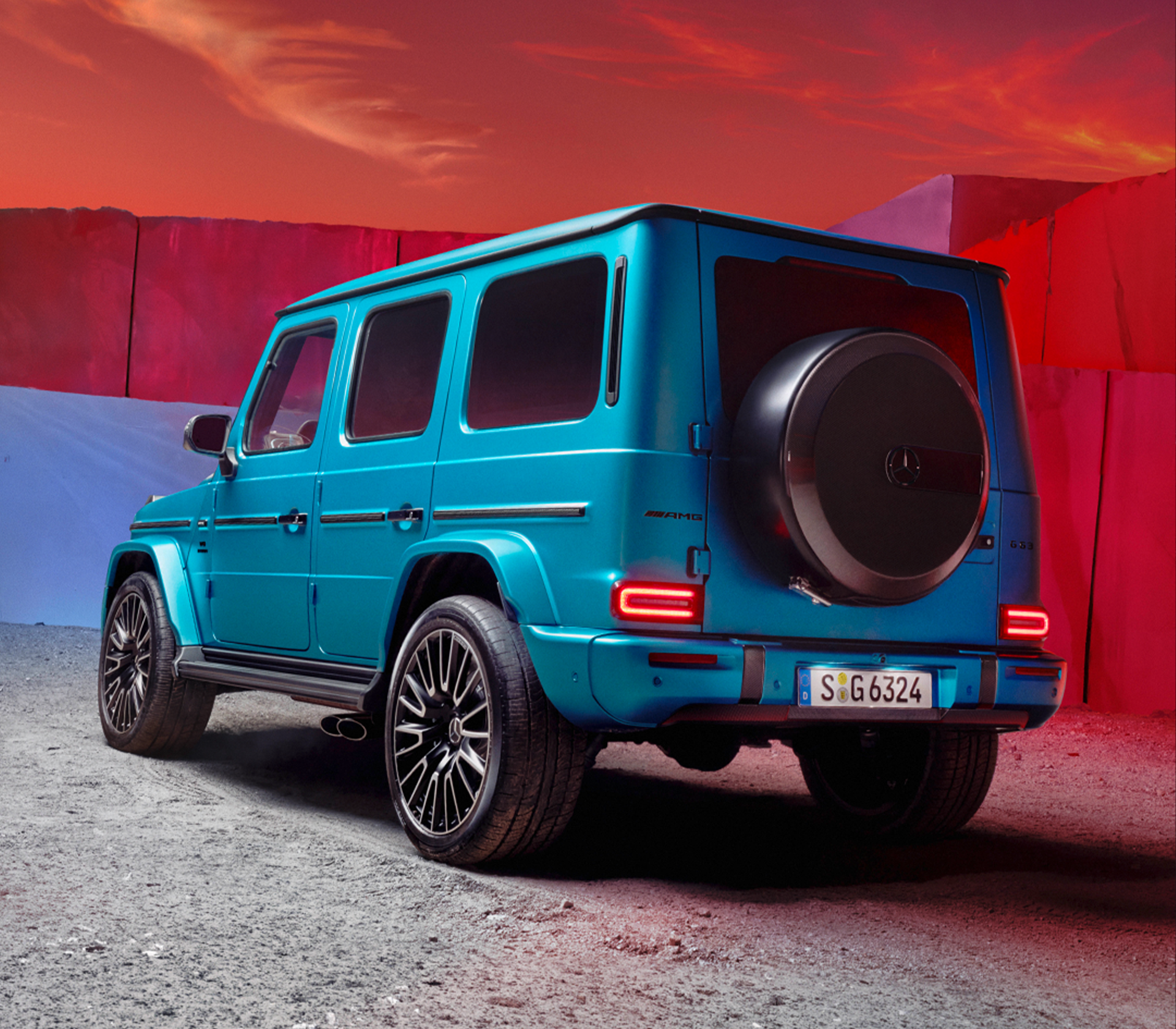 Mercedes-Benz G-Klasse in Blau Heckansicht und schräg von der Seite. Im Hintergrund ist der Himmel rot