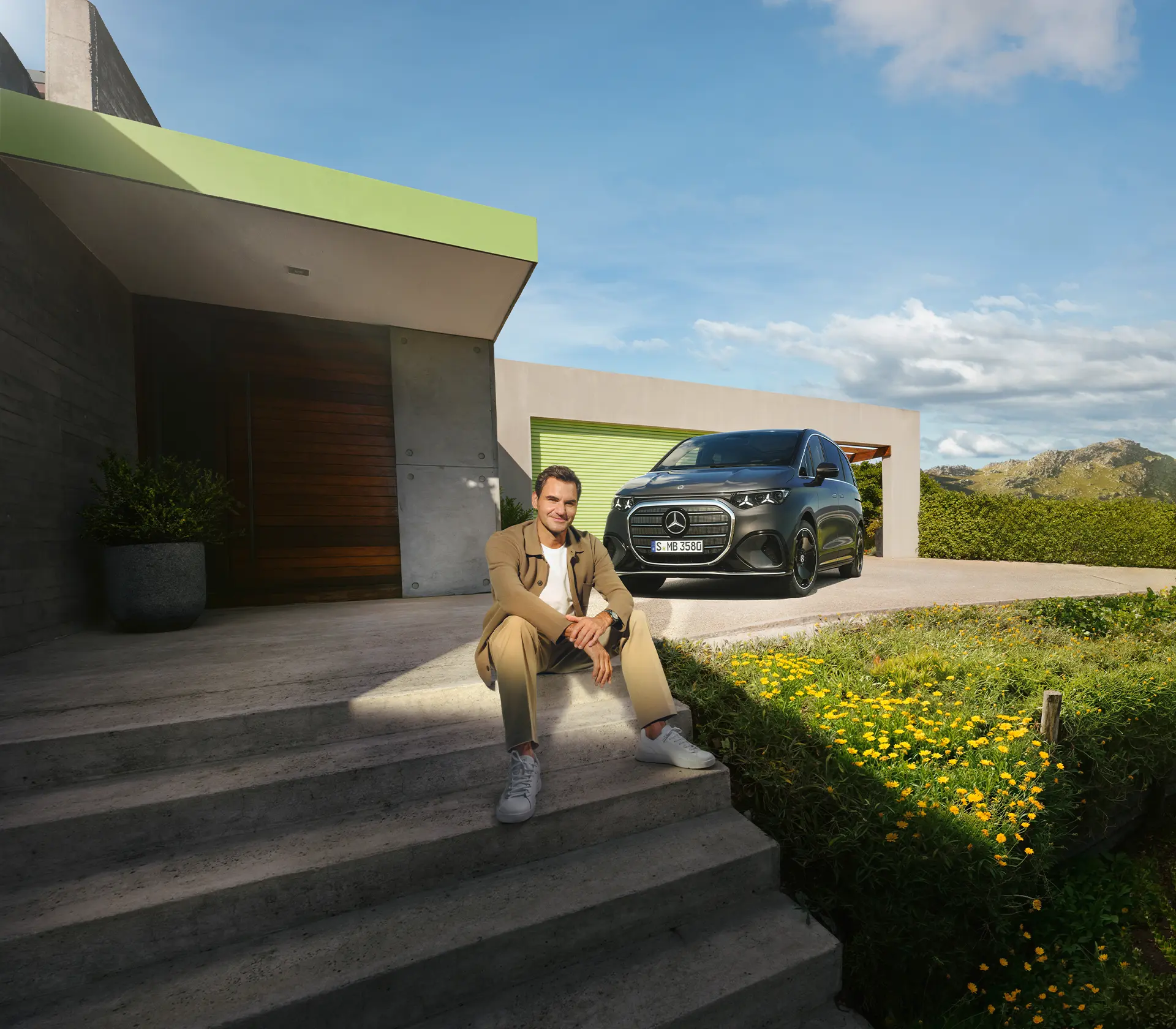 Mann sitzt auf Treppen vor einem Haus und dem neuen VLE