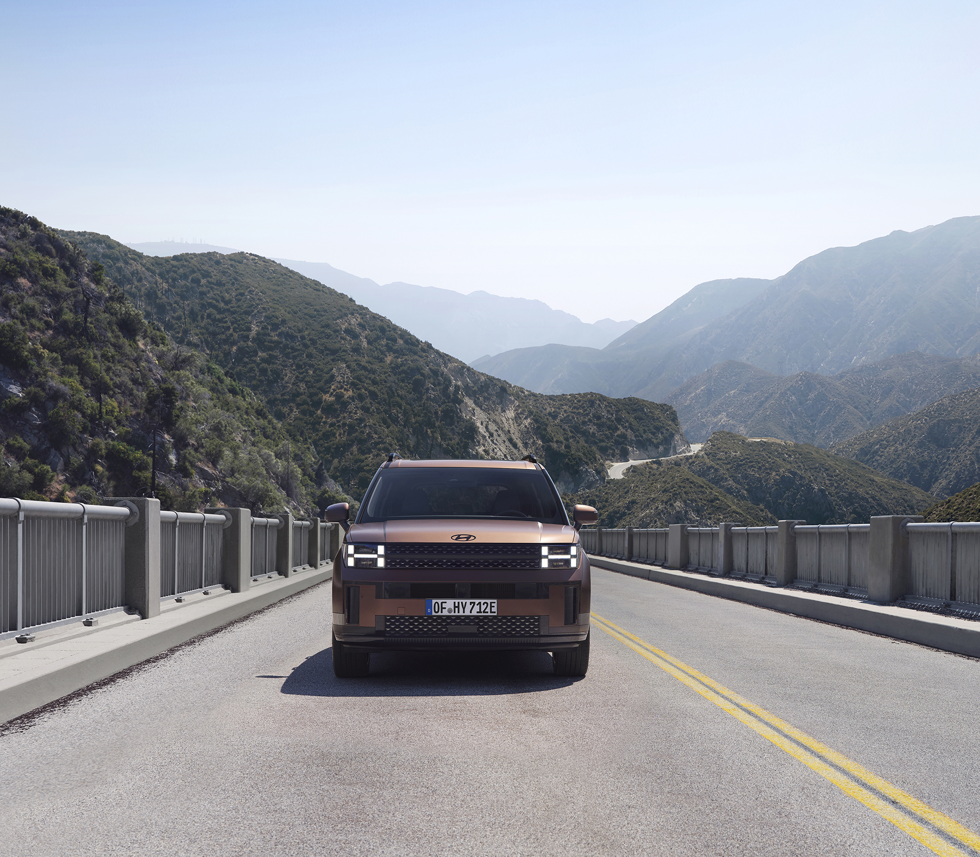 Hyundai SANTA FE  fährt auf einer Straße mit den Bergen und blauem Himmel im Hintergrund