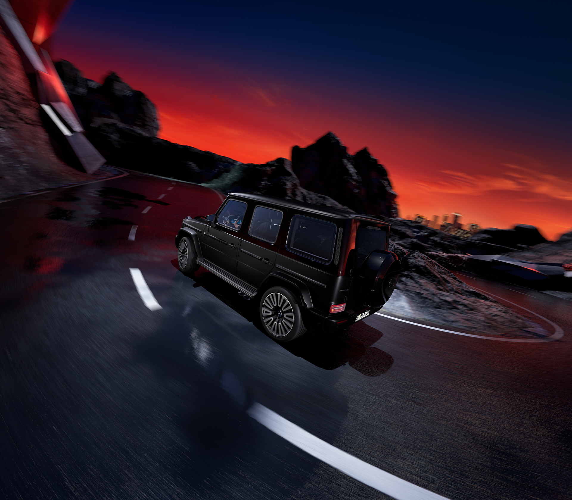 Mercedes-Benz G-Klasse in Schwarz fährt um eine Ecke. Um die Straße herum sind Felsen und der Himmel ist Rot-Blau