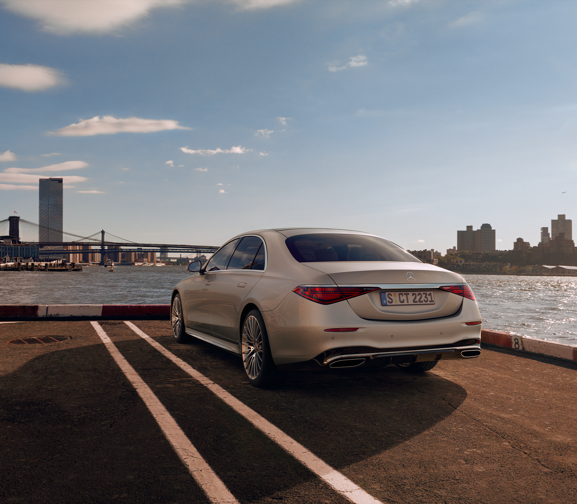 Mercedes-Benz S-Klasse grau während der Fahrt im Hintergrund sind große moderne Häuser, eine Brücke und Wasser