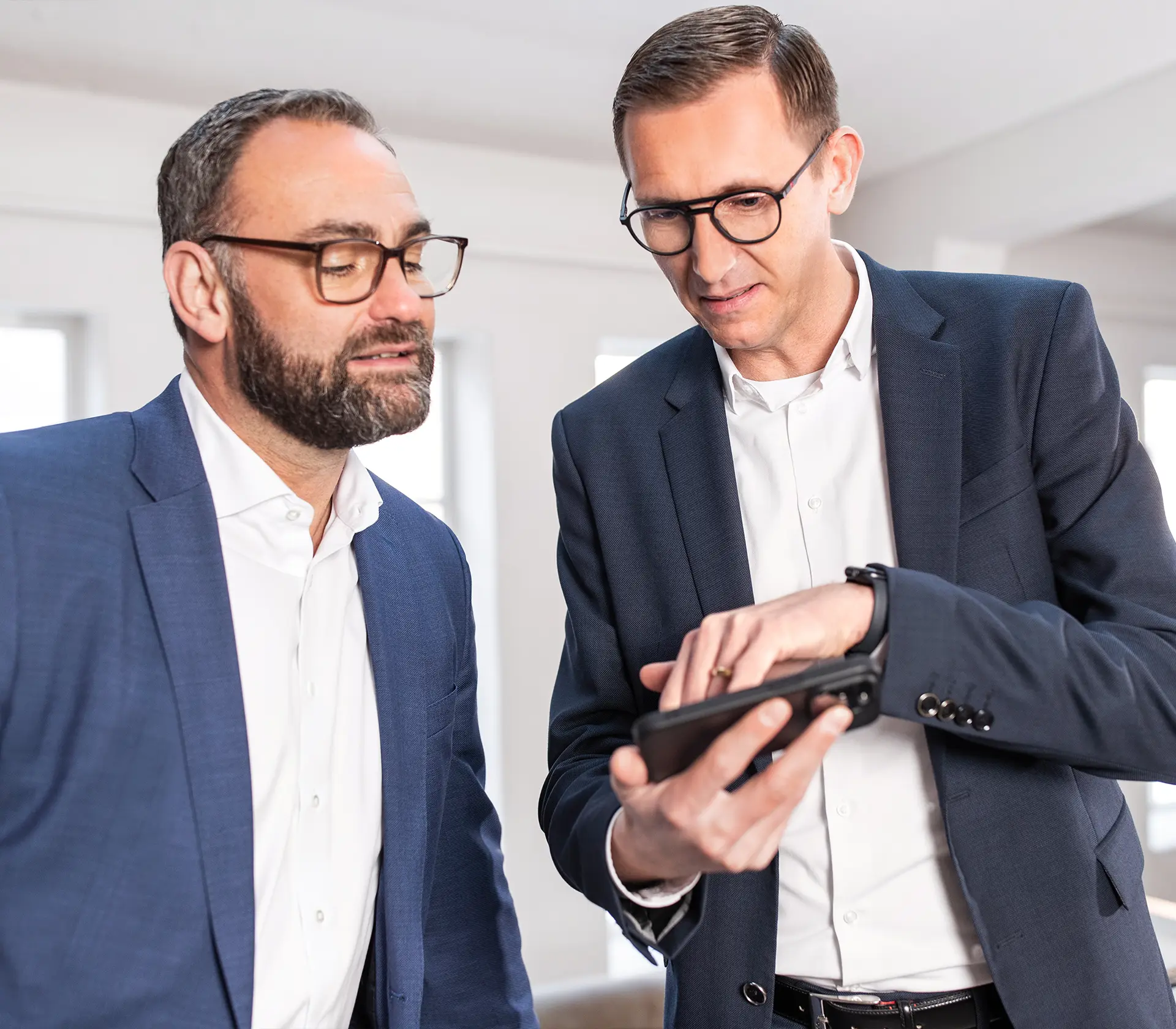 Flottenkundenverkäufer zeigt Kunden digital auf dem Handy eine mögliche Fuhrparkanalyse