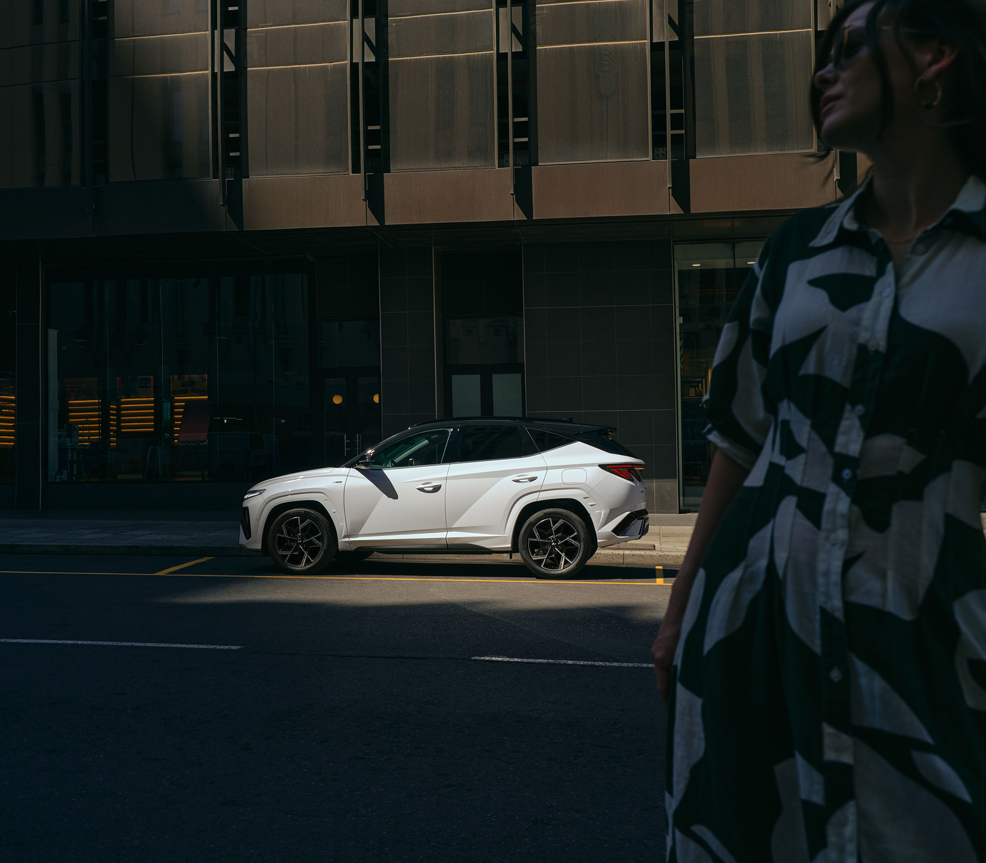 Hyundai TUCSON in weiß von der Seite, Foto dunkel im Vordergrund nur das Auto steht im Licht