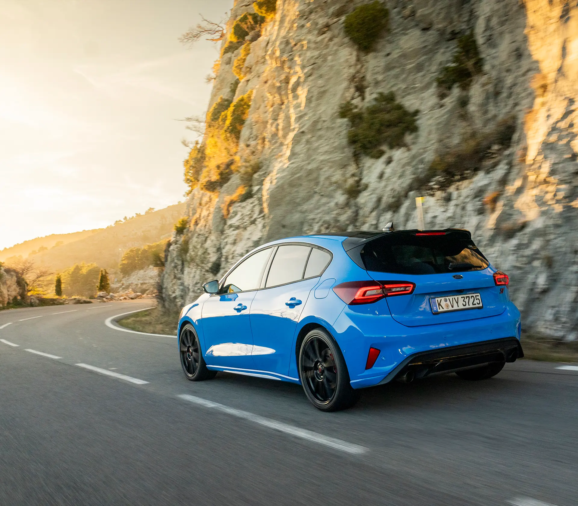 eine Heckansicht wie ein blauer Focus ST auf der Straße fährt