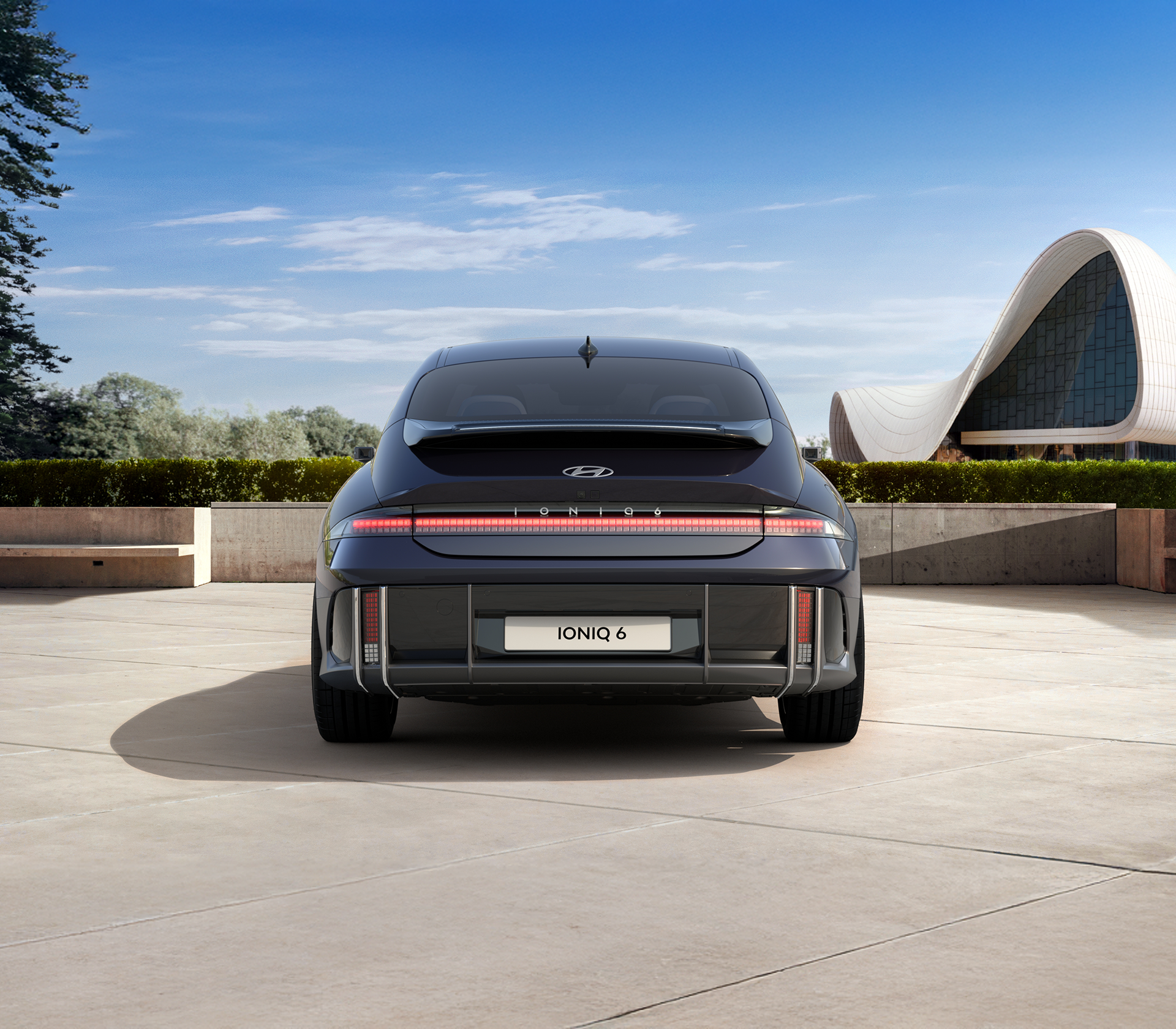 Hyundai IONIC 6 Heckansicht in schwarz, Hintergrund Himmel, Bäume und ein modernes Gebäude