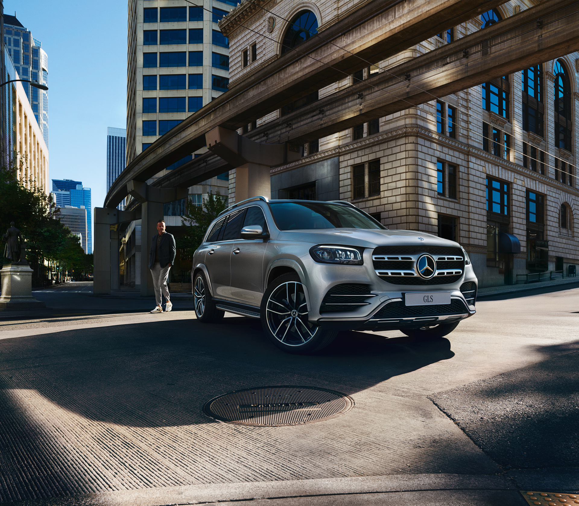 Mercedes-Benz GLS steht unter einer kleinen Brücke in einer Stadt und ein Mensch steht im bild