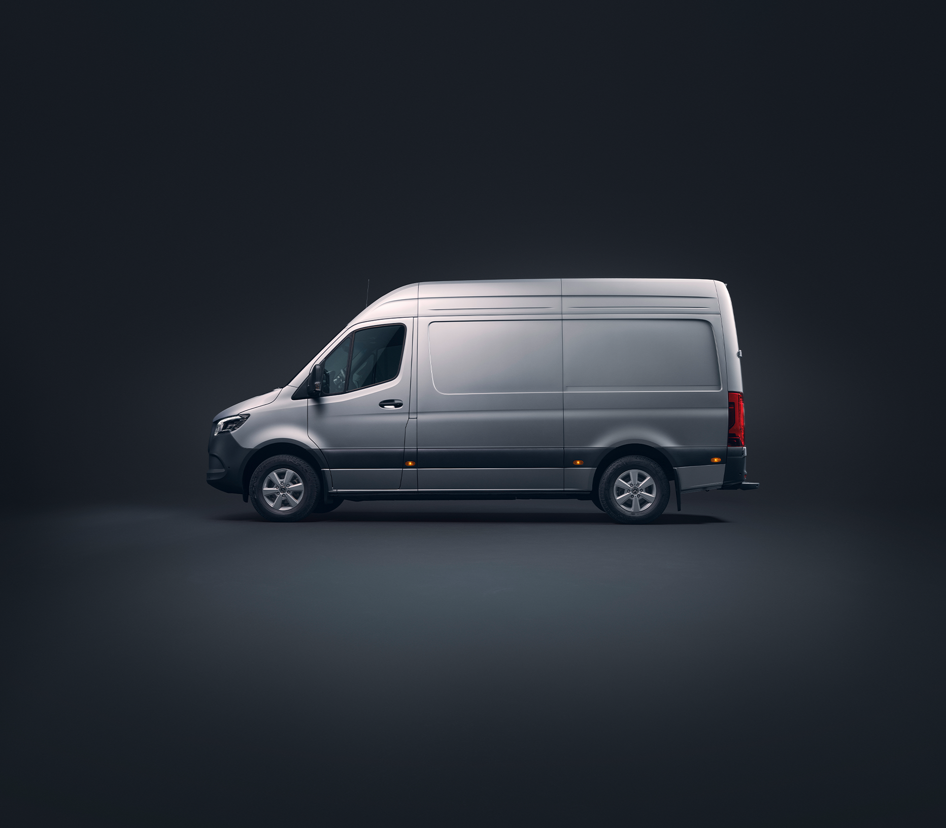 Mercedes-Benz Sprinter in grau von der Seite in einer schwarzen Studioumgebung