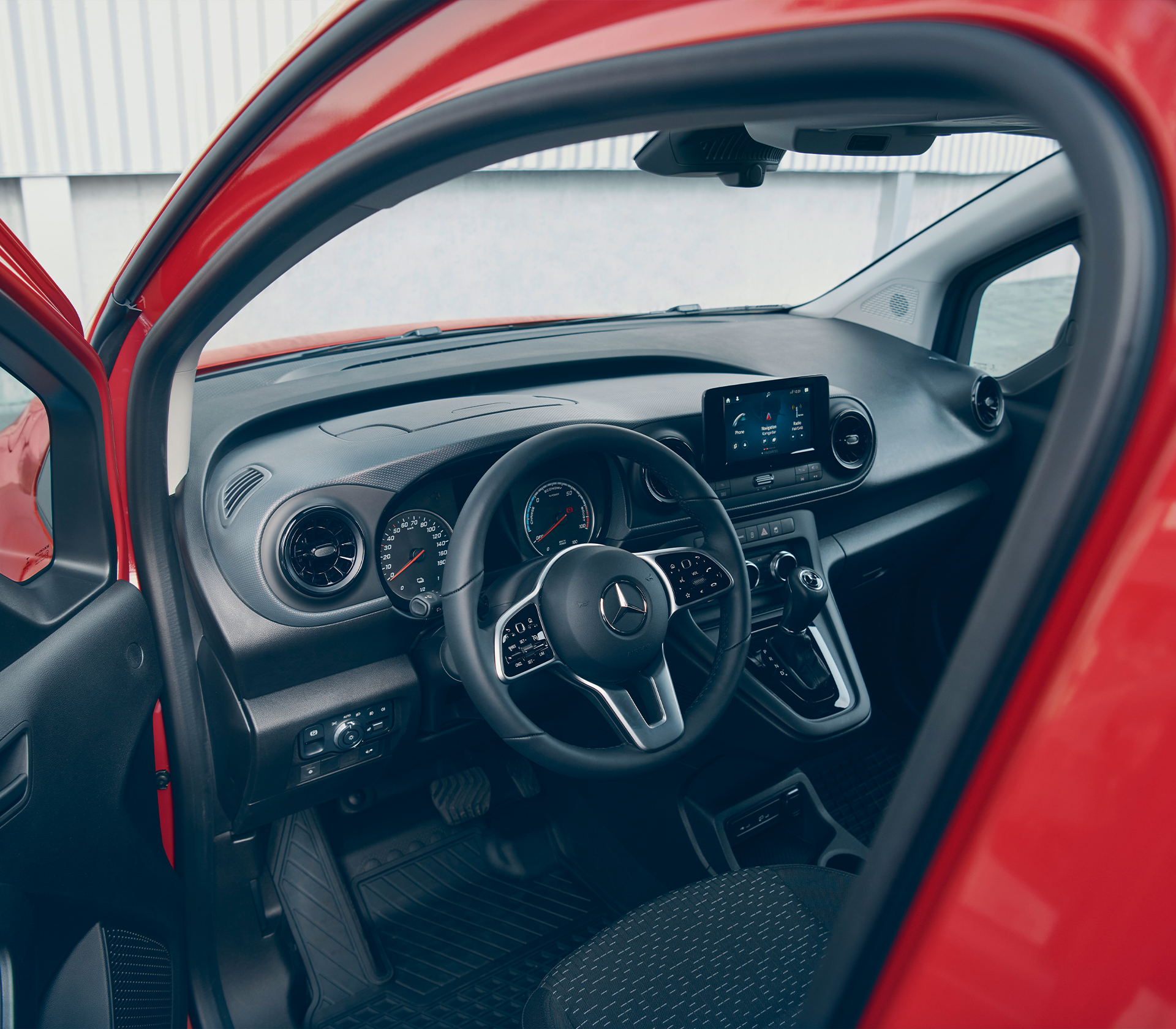 Einblick in den modernen Fahrerarbeitsplatz des Mercedes-Benz eCitan mit Multifunktionslenkrad, digitalem Cockpit und zentralem Touchscreen.