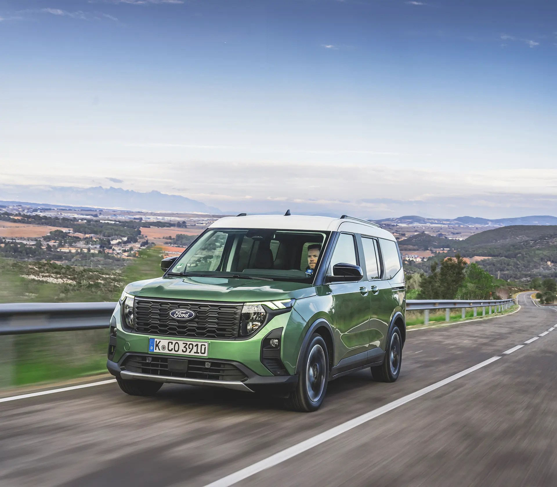 die Frontansicht auf einen grünen Tourneo Courier der auf der Straße fährt