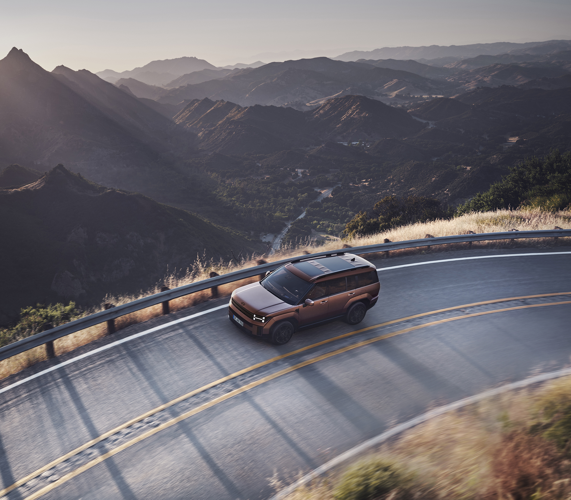 Hyundai SANTA FE von oben fotografiert fährt auf einer Landstraße in den Bergen mit abendlicht