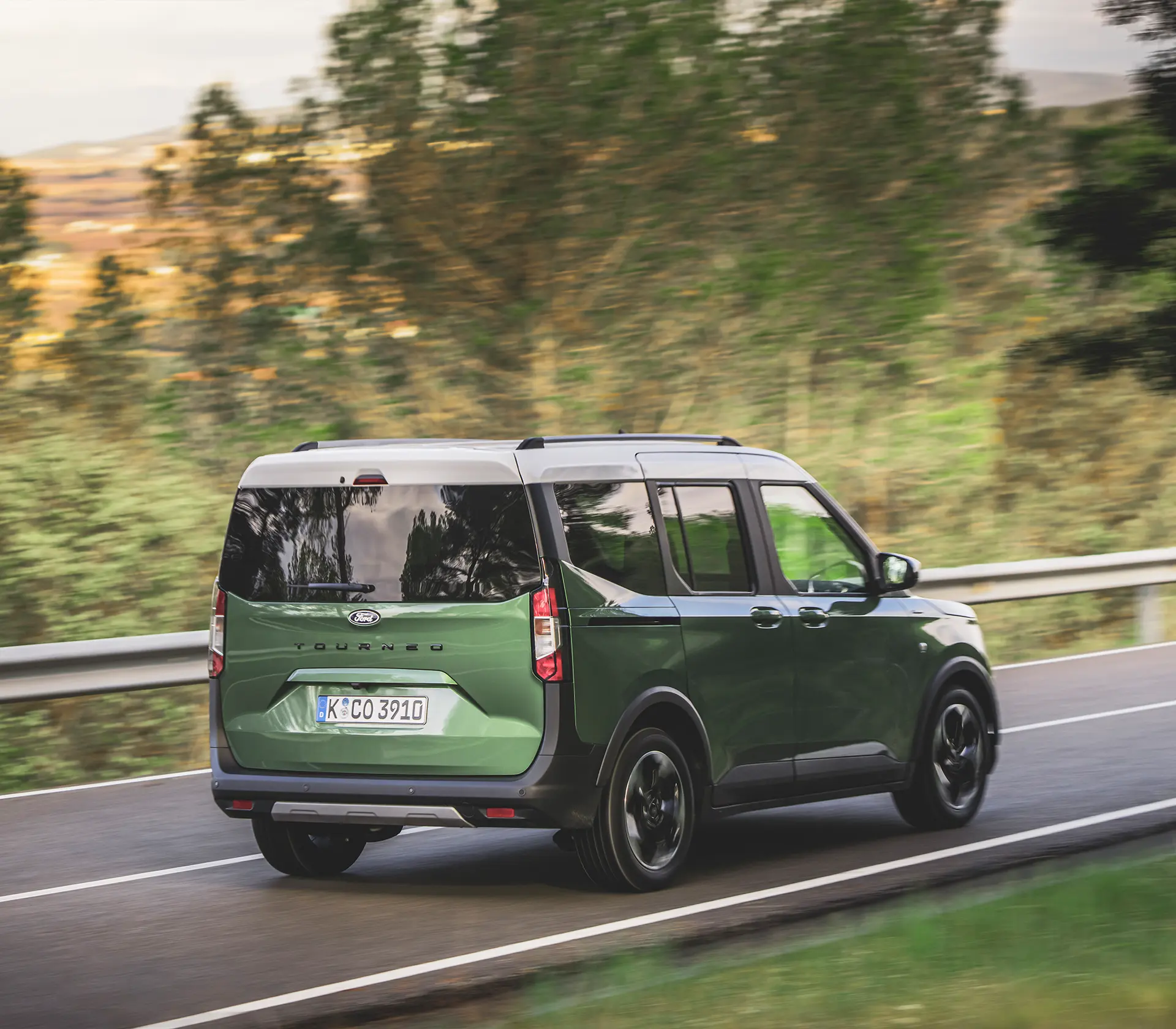 die Heckansicht auf einen grünen Tourneo Courier der auf der Straße fährt