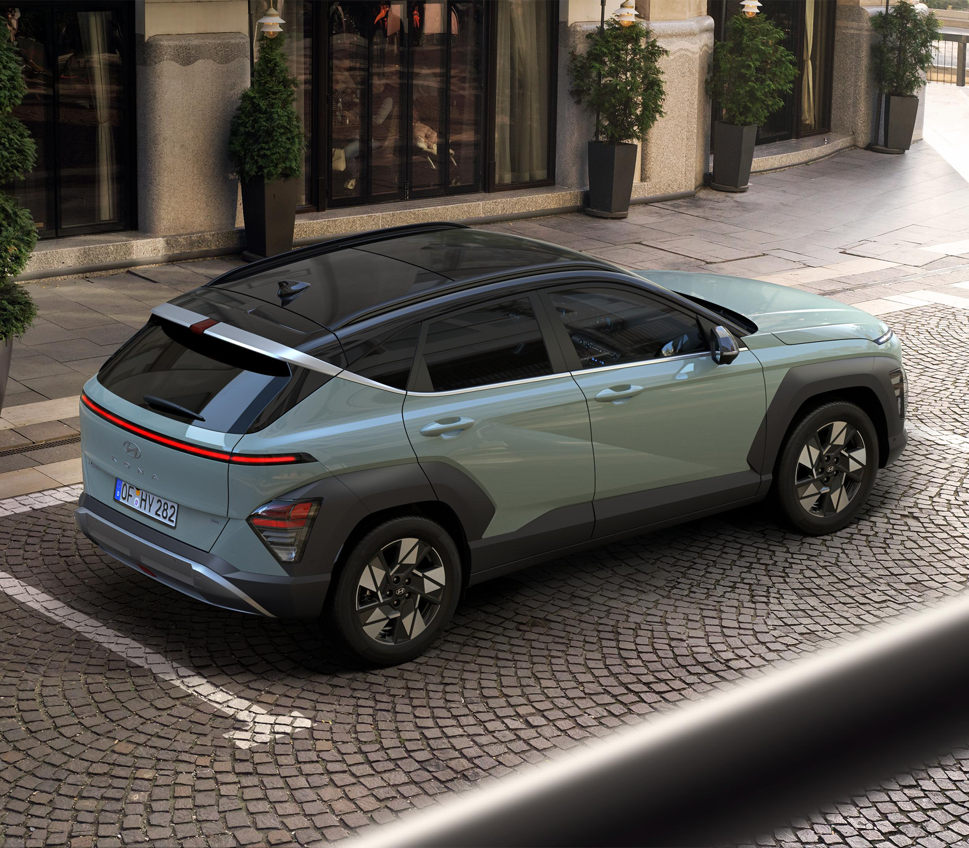 Hyundai KONA auf einem Parkplatz schräg von oben und mit einem Gebäude im Hintergrund