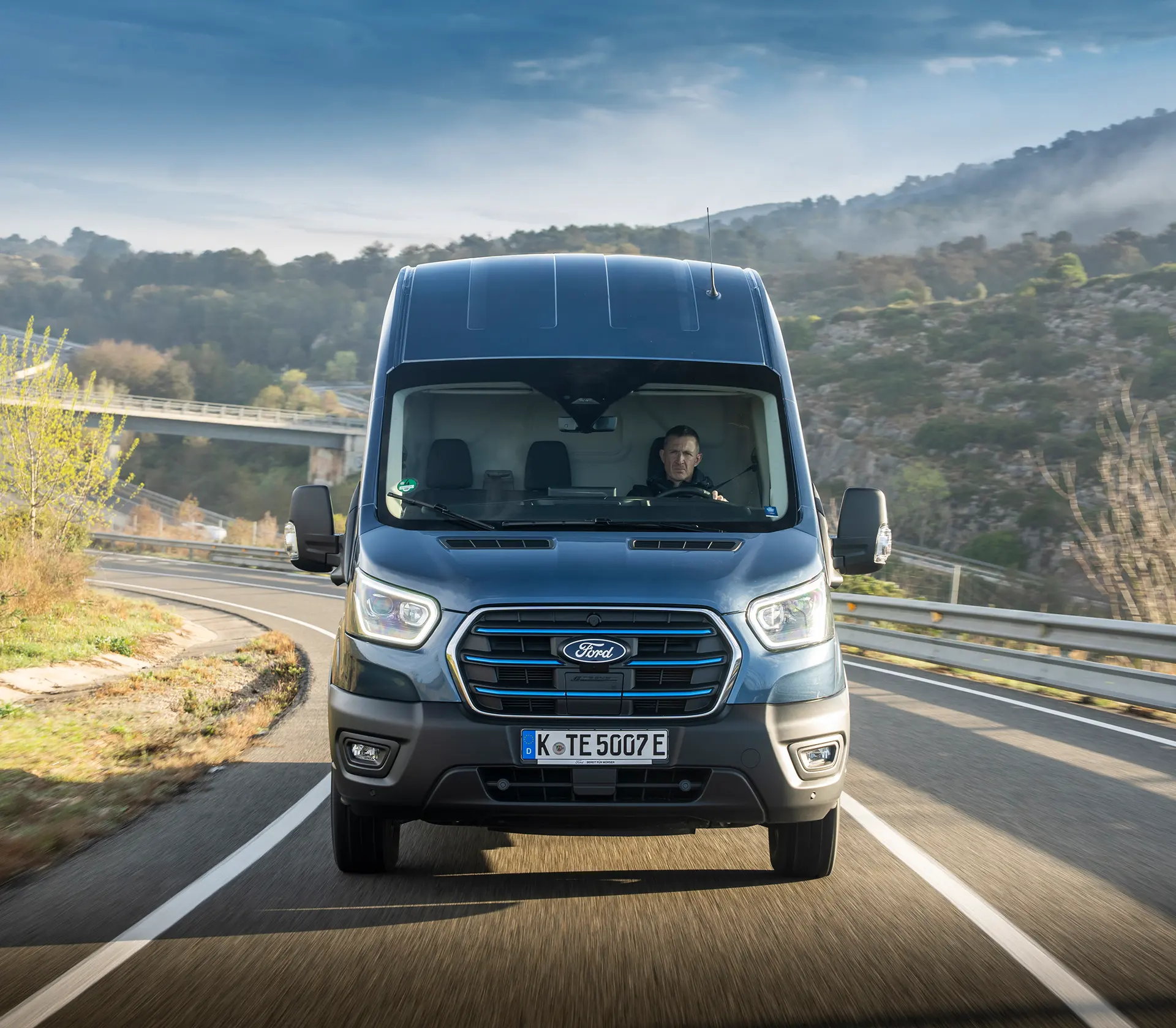 Frontansicht eines blauen E-Transit auf der Autobahn
