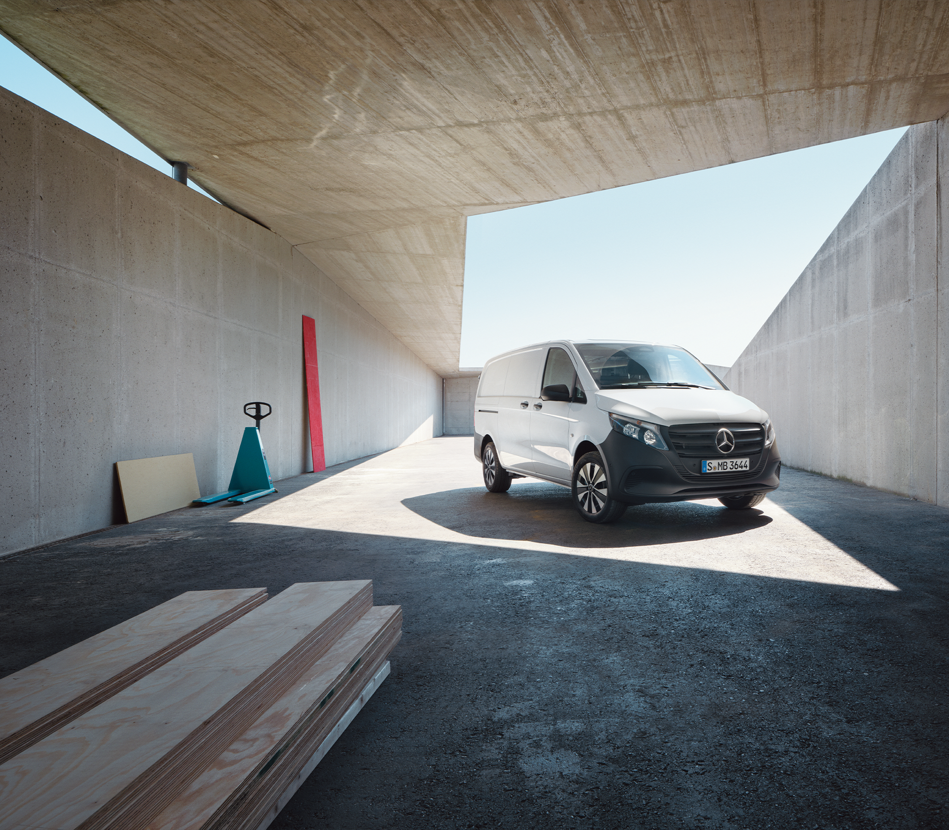 „Weißer Mercedes-Benz Vito vor moderner Industriearchitektur mit Laderampe und Tageslicht.“