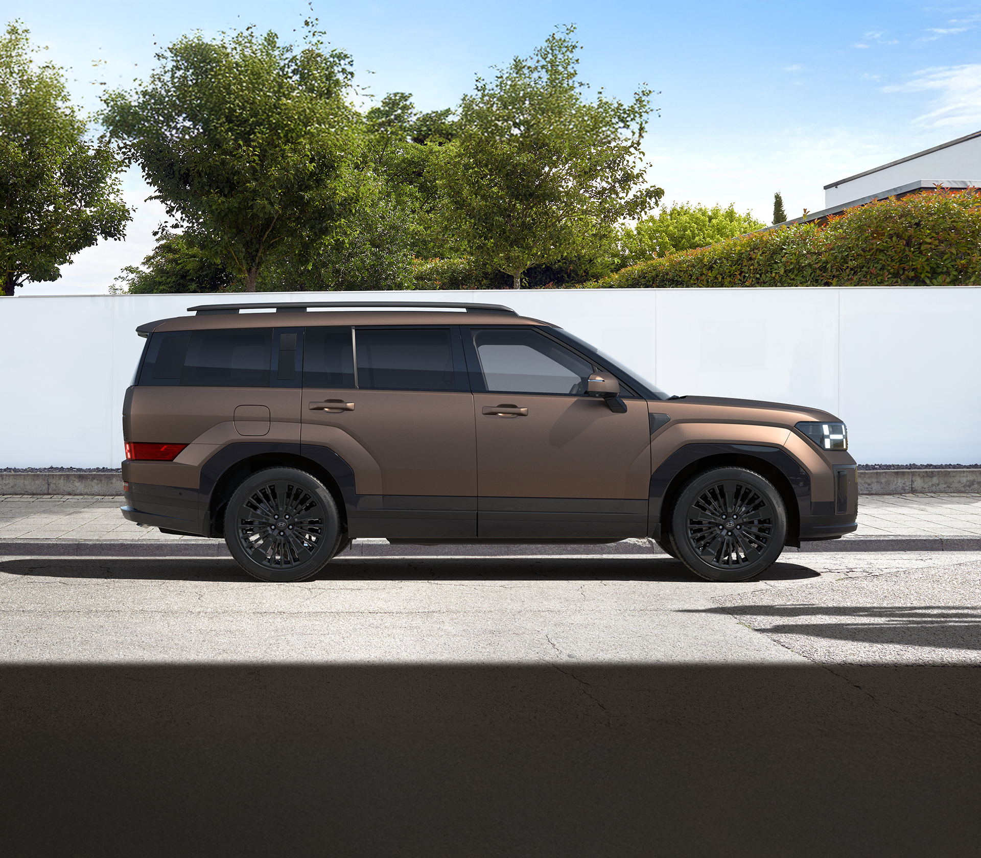 Hyundai SANTA FE von der Seite und einer weißen Mauer und grünen bäumen im Hintergrund